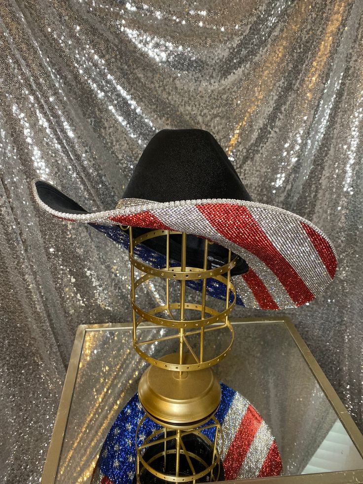 The “America” hat is perfect for your summer on the lake, BBQs, Labor day weekend, rodeos, and any events you may be attending! This hat will feature the American Flag print on the bottom. Choose whether you want crystal rhinestones on the top brim as well, or leave it plain with the crystal hat band that comes with it! **Please note - due to the bright colors on the American flag hat, they can fade over time, especially if they are exposed to rain or water** This hat features: Black straw hat U Americana Rodeo Hat With Curved Brim, Americana Curved Brim Hat For Rodeo, Americana Style Curved Brim Hat For Rodeo, Short Brim Rhinestone Hat For Kentucky Derby, Rhinestone Short Brim Hat For Kentucky Derby, Kentucky Derby Rhinestone Hat With Short Brim, Curved Brim Hats For Country Festivals, Rhinestone-embellished Short Brim Hat For Kentucky Derby, Country Style Rhinestone Hats For Rodeo