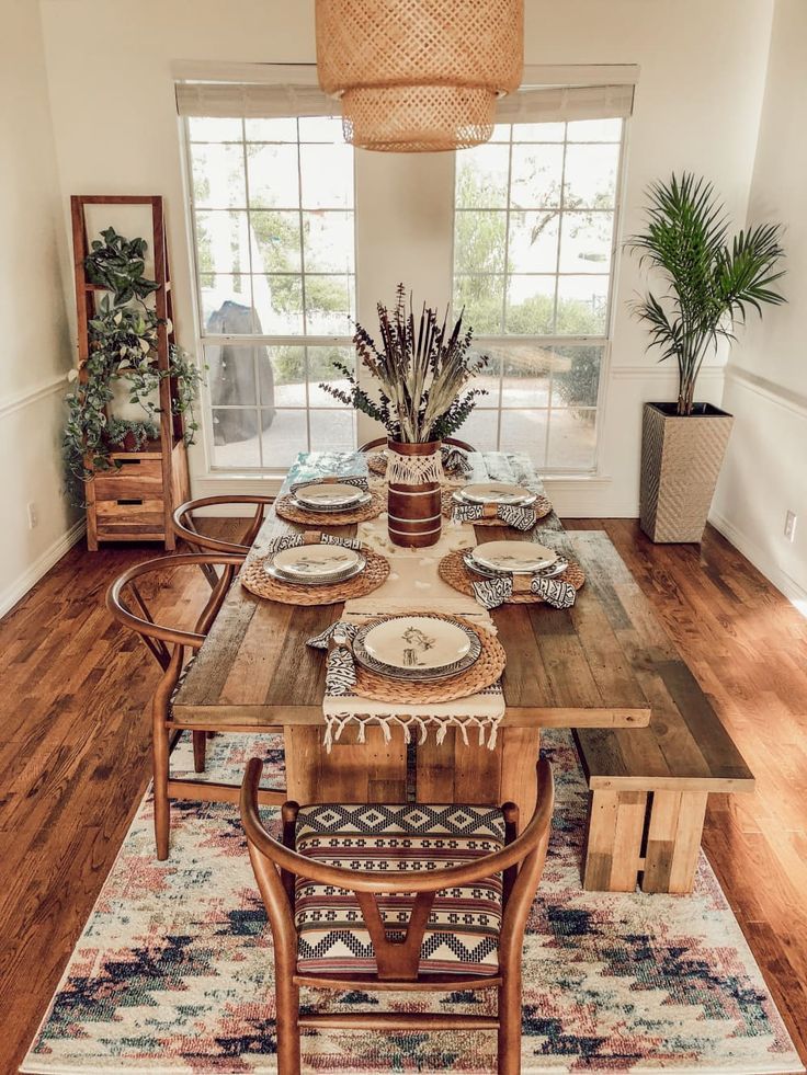 a dining room table set with place settings and plates on it, in front of a large window