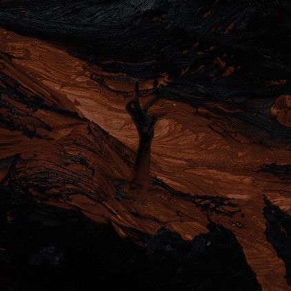 a lone tree stands in the middle of a rocky area at night, surrounded by dark rocks