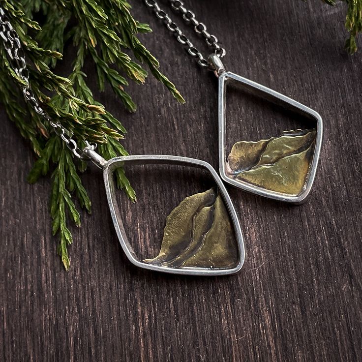 This Mixed Metal Mountain Ridge Necklace is a timelessly classic piece crafted with artisanal precision. Its solid brass mountain ridges are framed in sterling silver geometric shapes, hand-forged from sheet and wire by an artisan metalsmith. A luxurious yet understated accessory - perfect for any occasion. Metal Smithing Jewelry Ideas, Nature-inspired Sterling Silver Jewelry With Polished Finish, Minimalist Soldered Pendant Jewelry, Silver Nature-inspired Jewelry, Nature-inspired Jewelry Pendant With Oxidized Finish, Nature-inspired Oxidized Pendant Jewelry, Modern Brass Jewelry With Oxidized Finish, Modern Oxidized Brass Jewelry, Nature-inspired Pendant Jewelry With Oxidized Finish