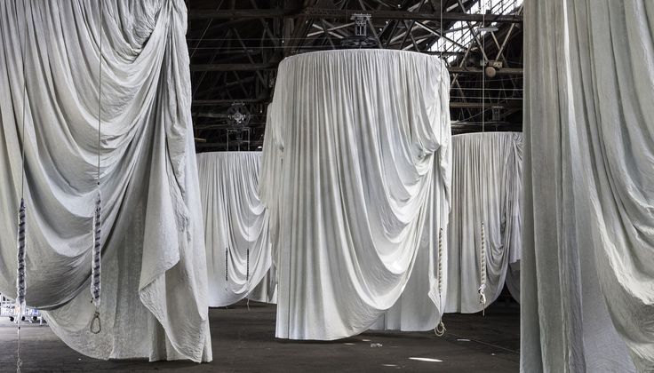 several white draped tables and chairs in an abandoned warehouse