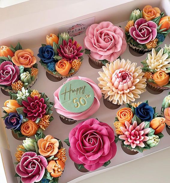 a box filled with cupcakes covered in frosting and decorated with colorful flowers