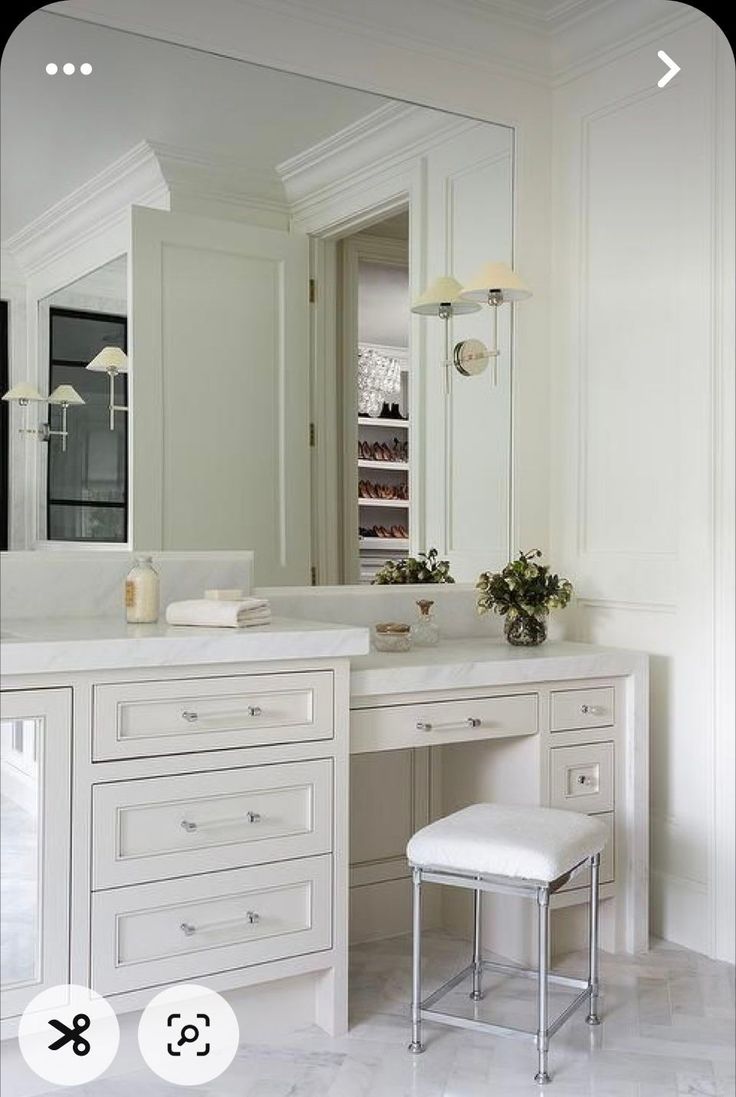 a white vanity with stool and mirror in a room that is well lit by lights