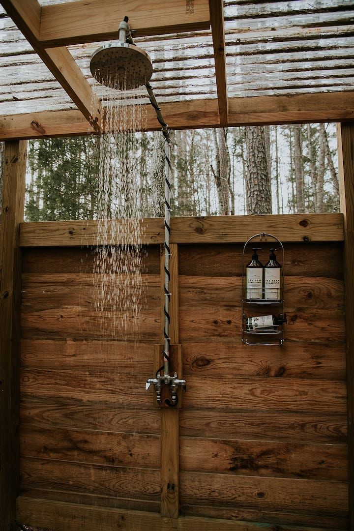 a shower head with water coming out of it's spout in front of a wooden wall