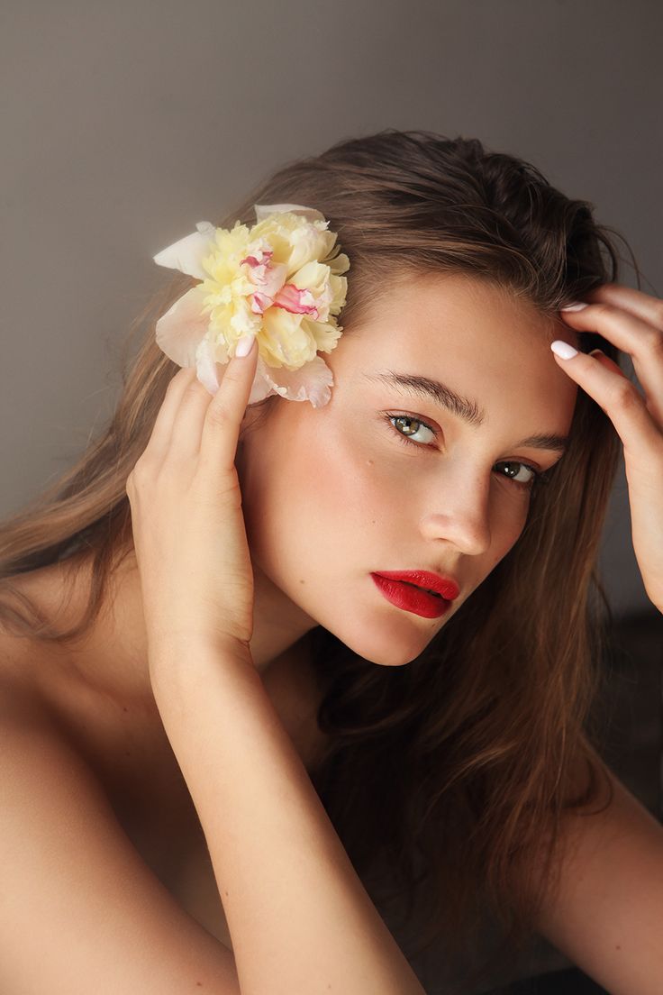 a woman with long hair and a flower in her hair is posing for the camera