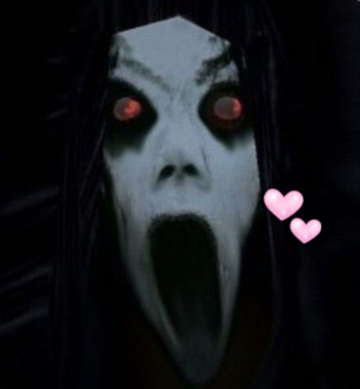 an evil looking person with red eyes and long black hair is in front of a heart shaped object