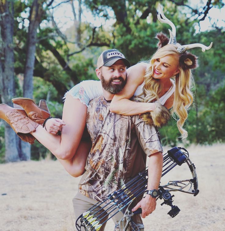 a man carrying a woman on his back in the woods with deer antlers on their head