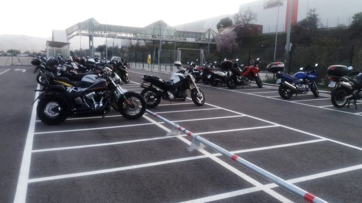 a group of motorcycles parked in a parking lot next to each other on the street