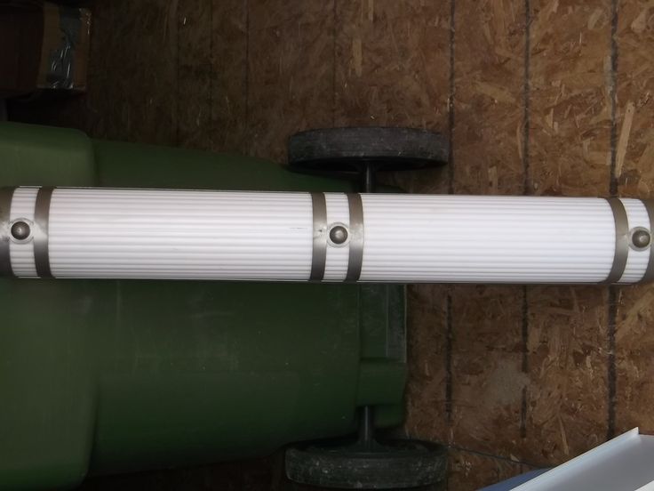 a white pipe is attached to the side of a green tank in a storage area