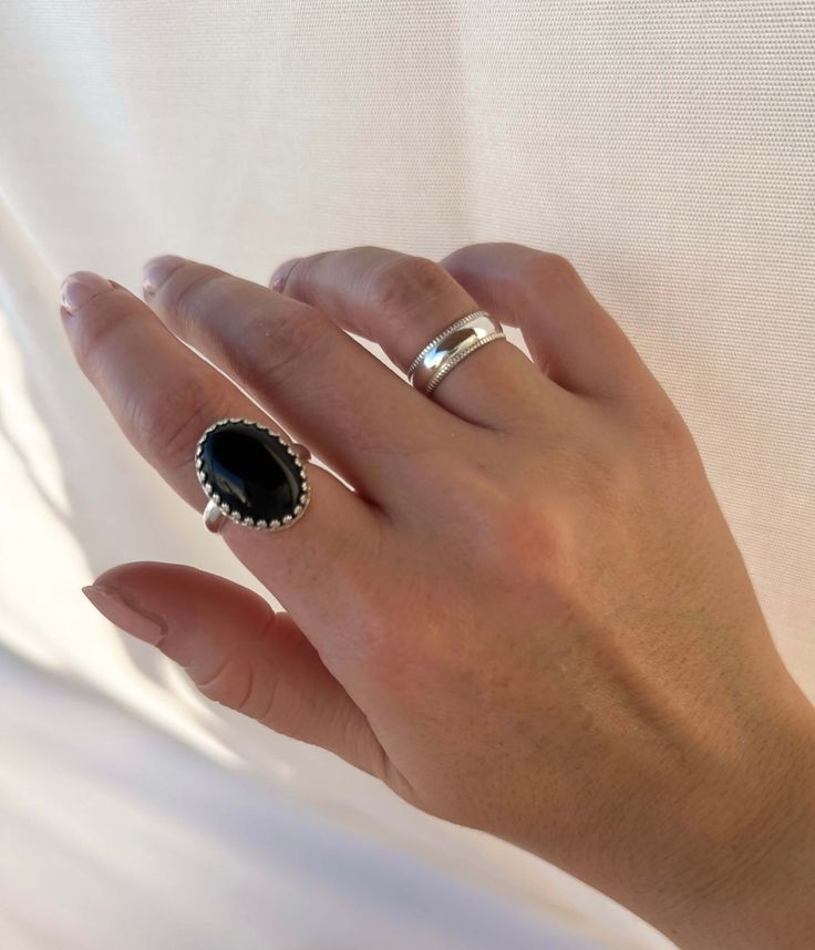 This Midnight Ring features a large black Onyx stone set in a sterling silver setting, making it a statement ring that is both elegant and bold. The black stone is believed to bring balance, protection, and stability to the wearer, making this ring not only a beautiful accessory but also a powerful and meaningful piece. Stone size: 18x13 mm Sterling SilverBand width: 3 mm Made to order. Please allow 7 business days for processing. Dot Ring, Simple Band, Bold Rings, Dome Ring, Ear Cuff Earings, Black Onyx Stone, Jewelry Lookbook, Domed Ring, Onyx Stone