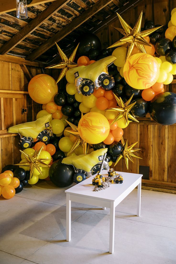 a room filled with lots of balloons and stars on the wall next to a table