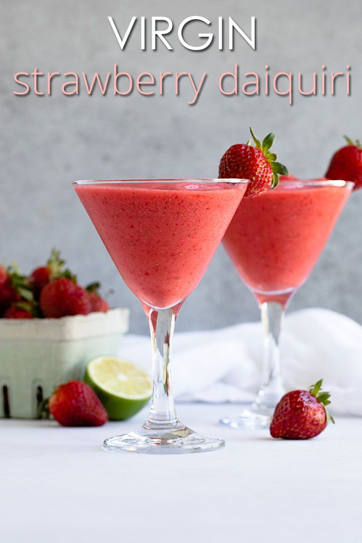 two glasses filled with strawberry margaritas next to sliced strawberries