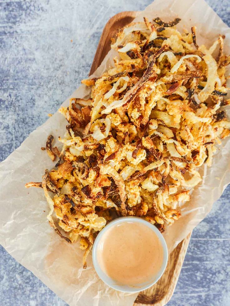 a wooden tray topped with fried food next to a cup of coffee