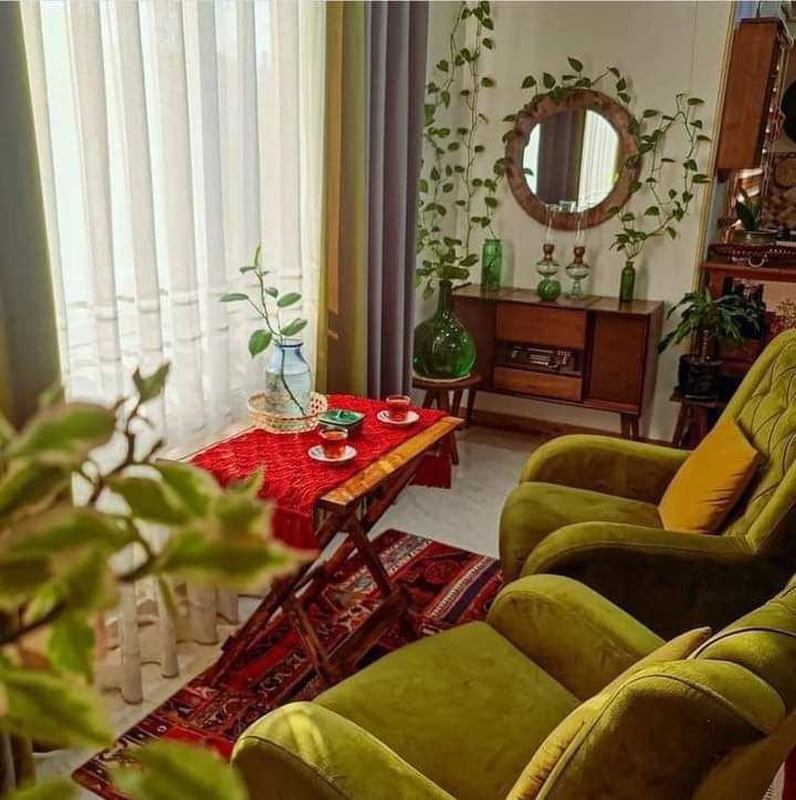 a living room filled with green furniture and plants on top of a red carpeted floor