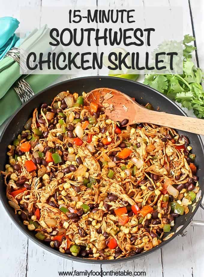 a skillet filled with chicken, beans and veggies on top of a white wooden table