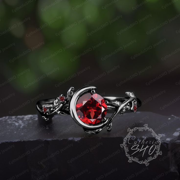 a red stone ring sitting on top of a black surface