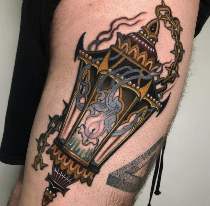 a close up of a person's leg with a tattoo on it and a lantern