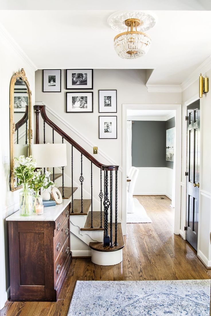 an entryway with pictures on the wall and a rug in front of it, along with a stair case