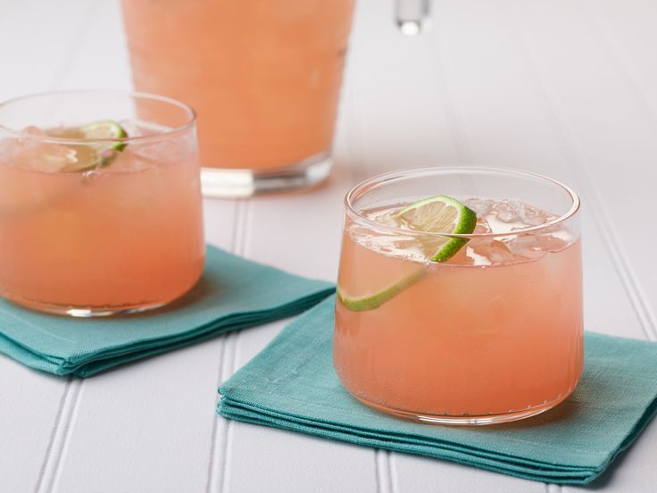 two glasses filled with pink lemonade and lime on top of blue napkins next to each other