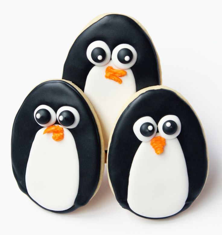 three decorated penguin cookies sitting next to each other