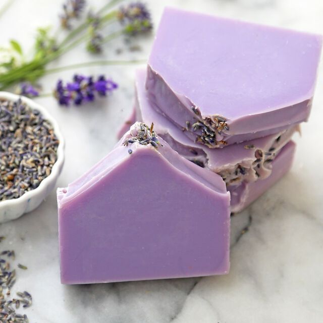 three bars of soap sitting on top of each other next to lavender flowers and a small bowl