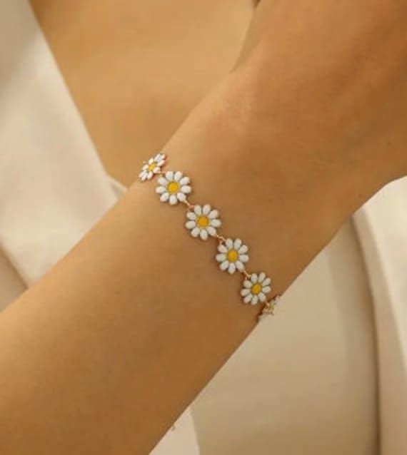 a woman wearing a bracelet with daisies on it