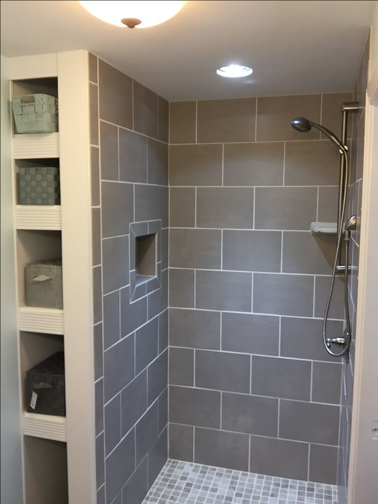 a walk in shower sitting next to a white shelf