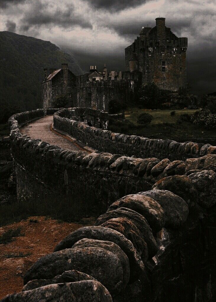 an old castle sits on top of a hill under a cloudy sky with dark clouds