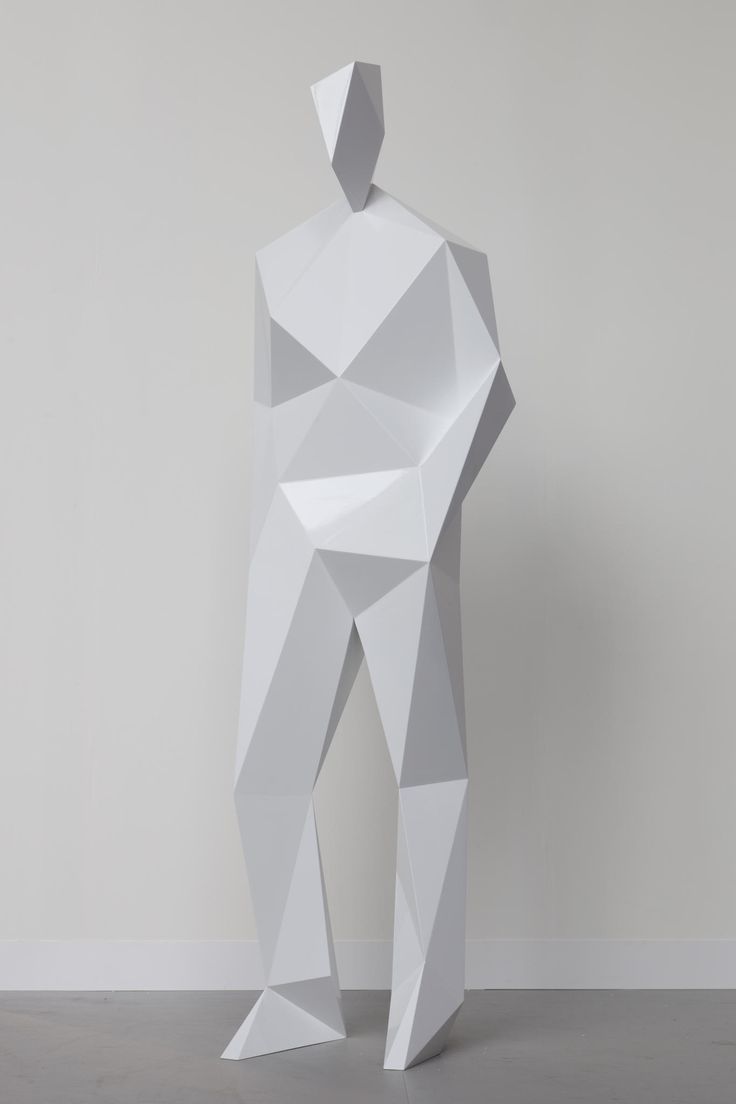 an abstract white sculpture stands in front of a gray wall