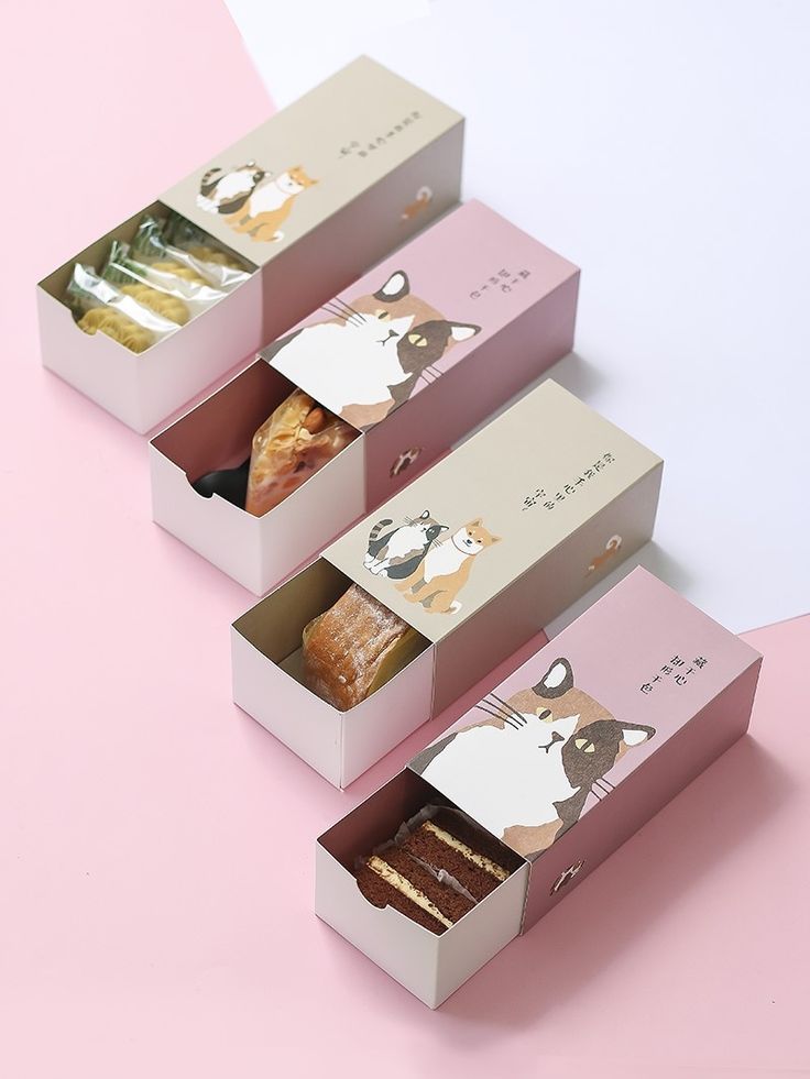 three boxes filled with different types of pastries on top of a pink tablecloth