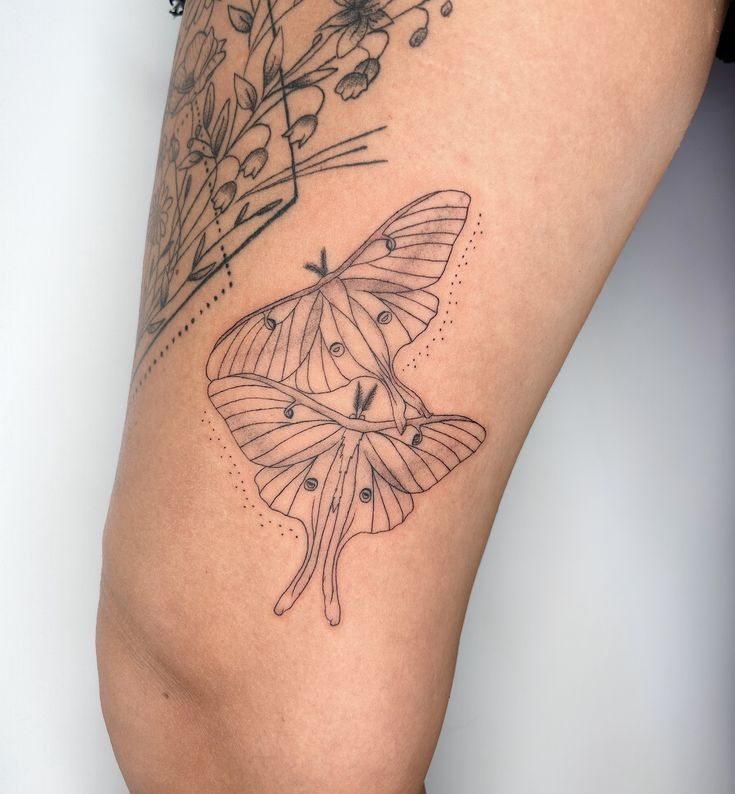 a close up of a tattoo on the leg of a person with a butterfly and flowers