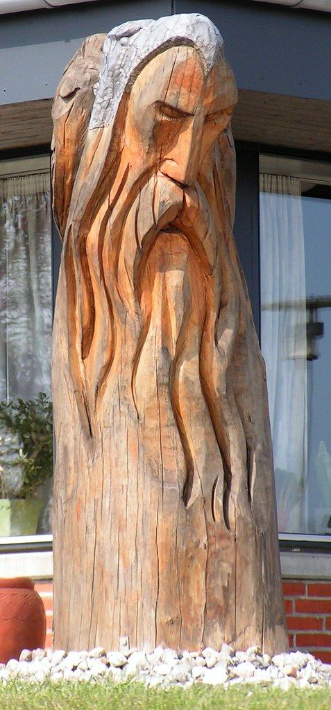 a wooden carving of a man's face in front of a building with windows