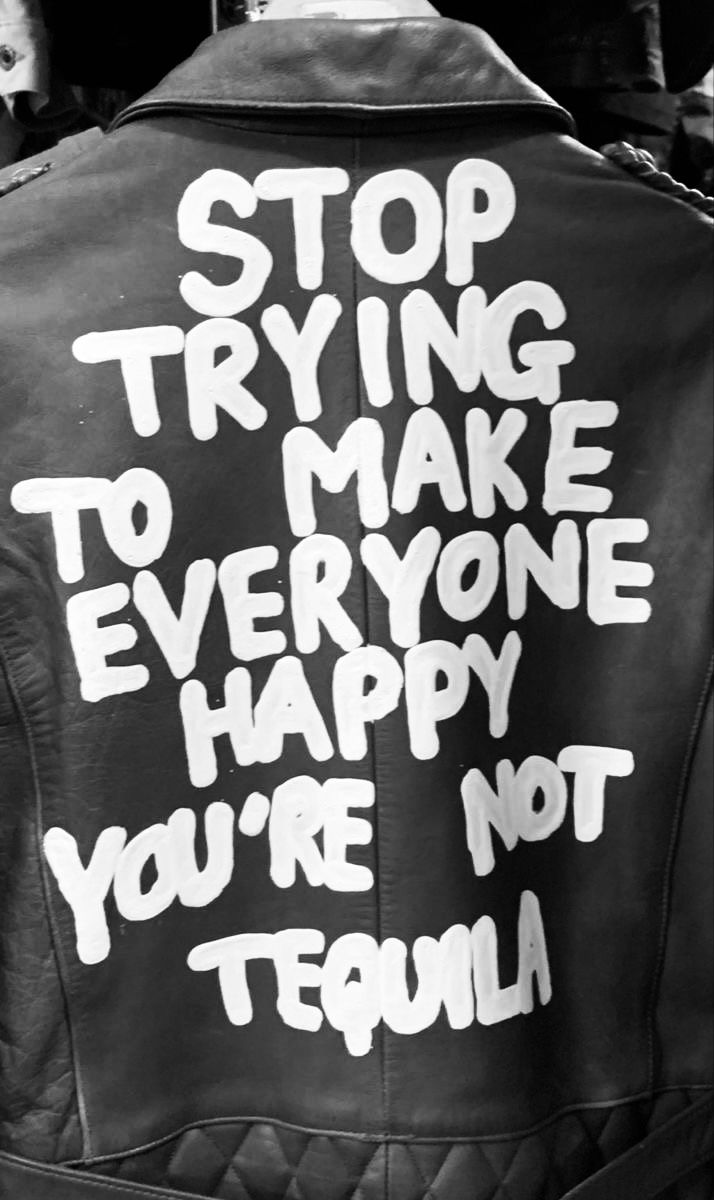 a black and white photo of a leather jacket with writing on the back that says stop trying to make everyone happy you're not team