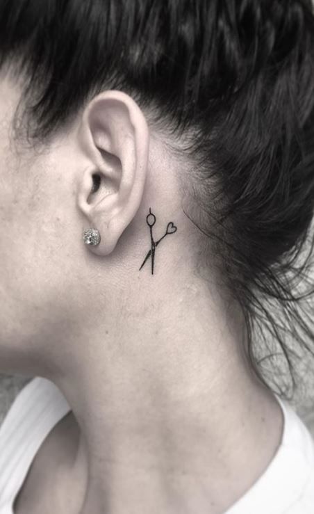 a woman with a small tattoo on her neck and behind her ear is a pair of scissors