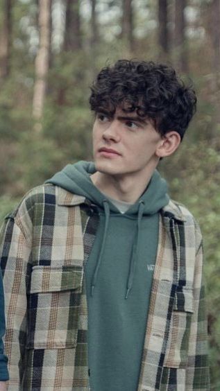 two young men standing next to each other in the woods