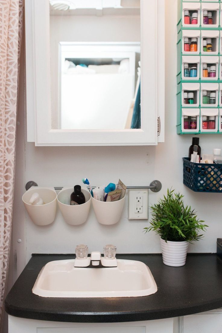 a bathroom sink sitting under a mirror next to a potted plant and other items