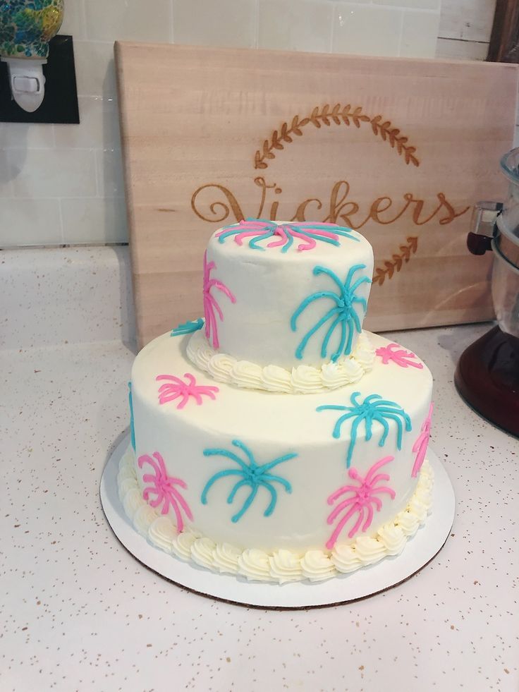 a three tiered cake with palm trees on the bottom and pink, blue, and white frosting