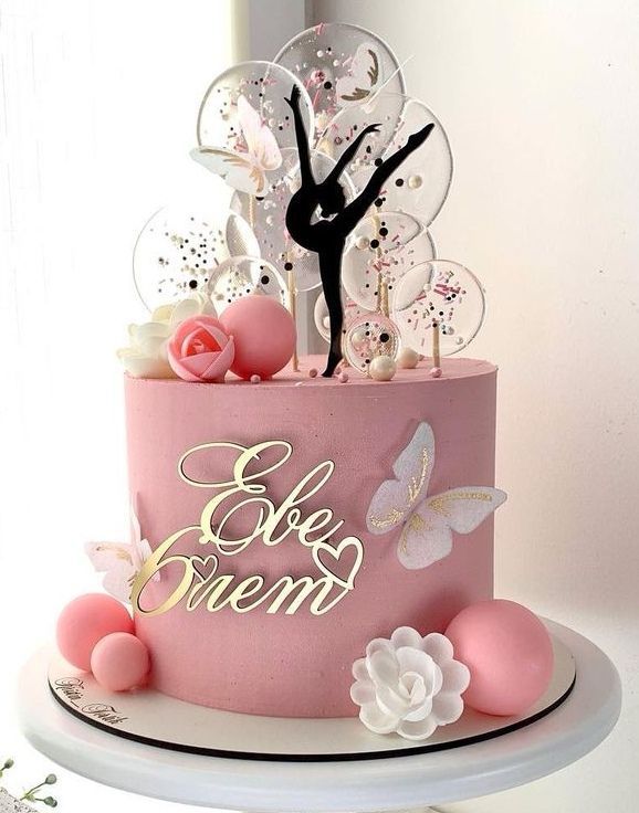 there is a pink cake that has a figure on top and flowers in the middle