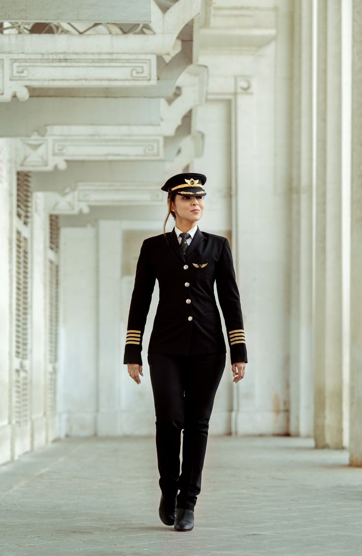 a woman dressed in an air force uniform walking down a hallway with columns on both sides