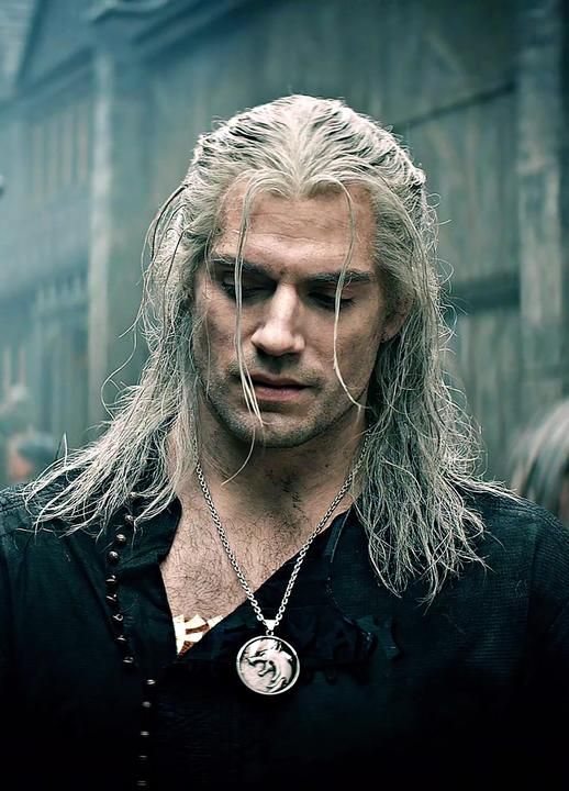 a man with long grey hair wearing a black shirt and silver necklace on his neck