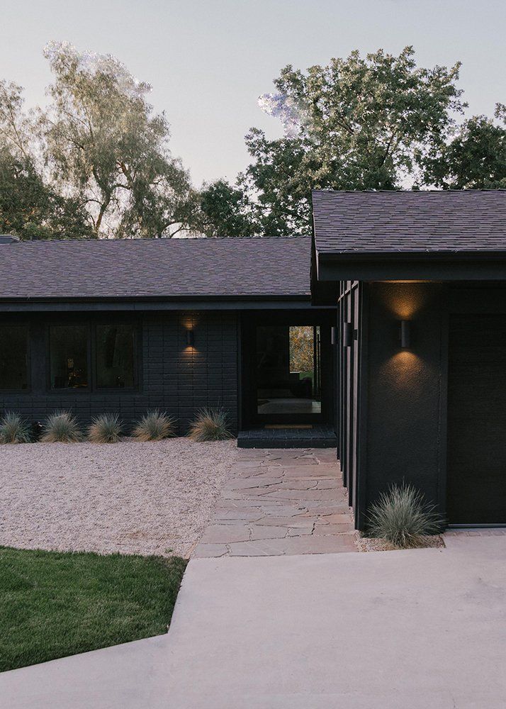 a black house with two garages and lights on