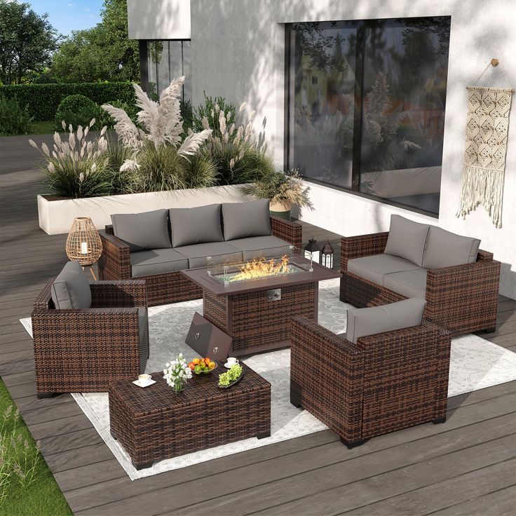 an outdoor living room with wicker furniture and fire pit in the middle of it