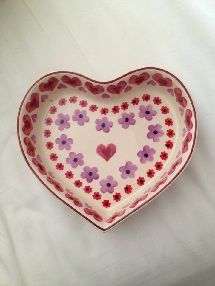 a heart shaped bowl with flowers painted on the bottom and sides, sitting on a white surface