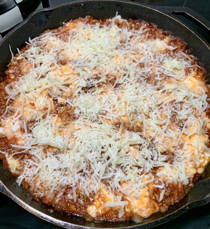 an uncooked pizza with cheese and sauce in a skillet on the stove