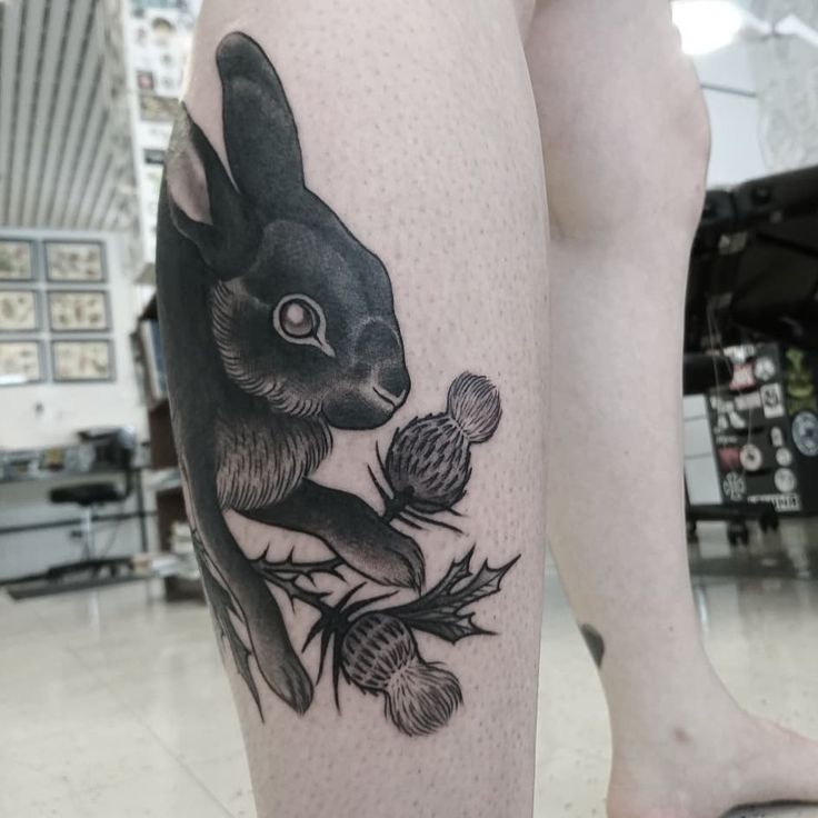 a black and white tattoo of a rabbit on the leg