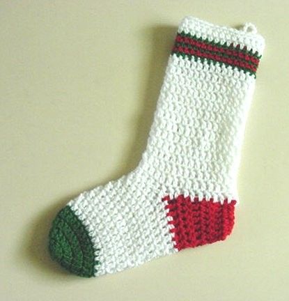 a crocheted christmas stocking is laying on the floor next to a white wall