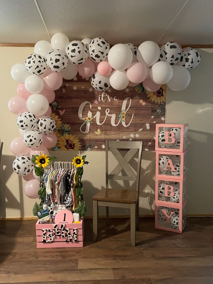 a baby shower with balloons and sunflowers on the wall next to a chair