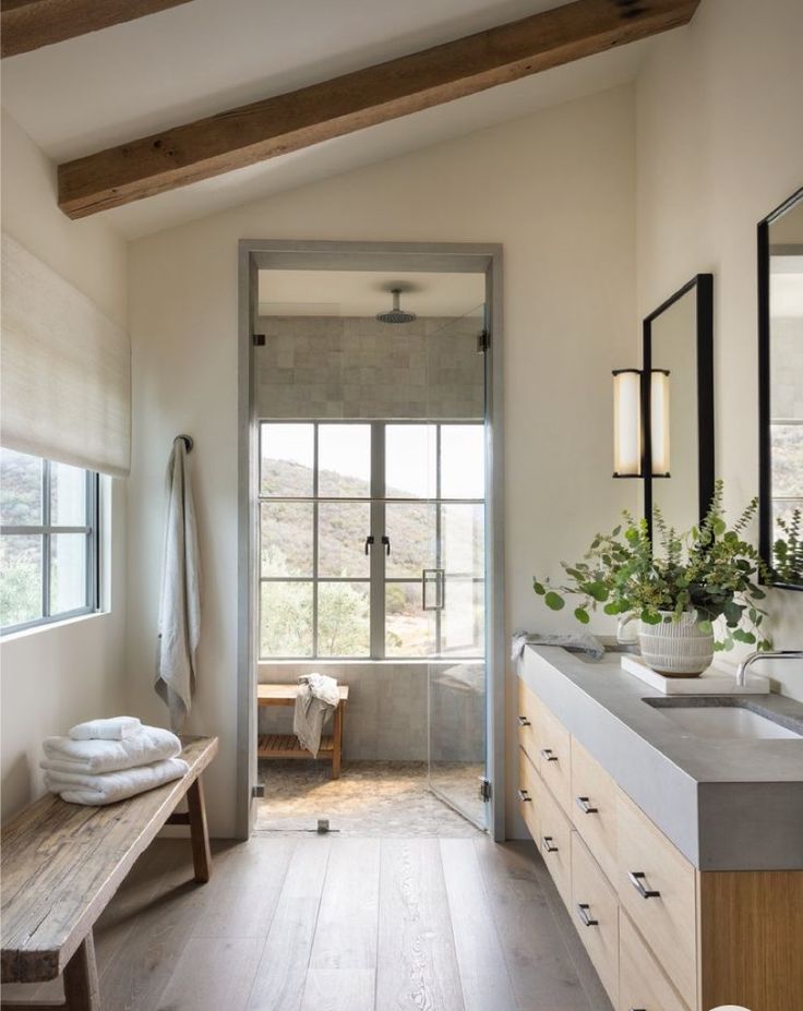 a large bathroom with wood floors and white walls, along with a wooden bench in the middle