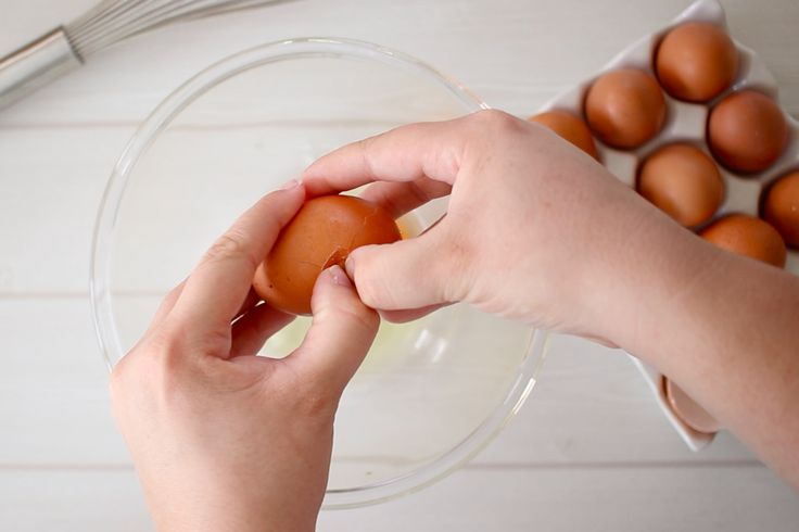 a person is peeling an egg into a bowl