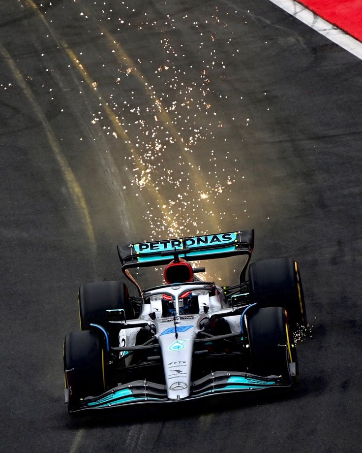 a race car driving down the track with fireworks in the air above it and on to the ground